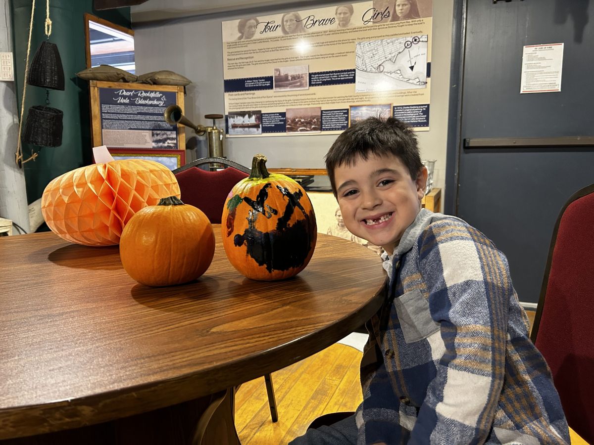 Smiling caucasian little girl showing her painted pumpkin